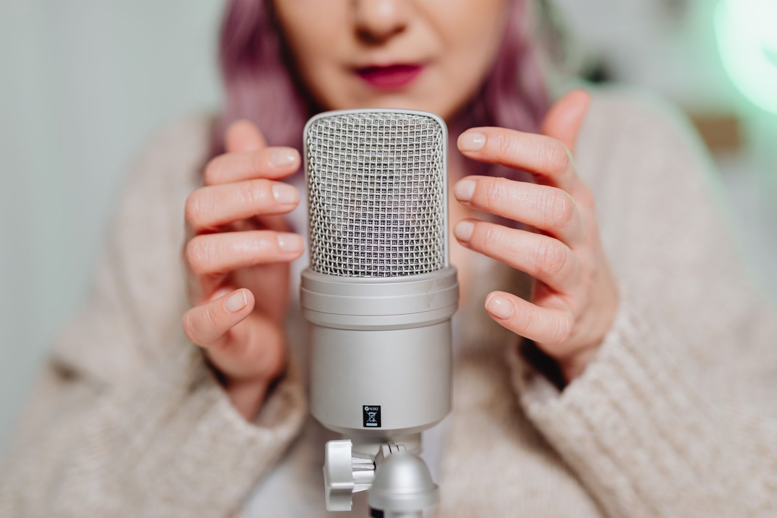 Microfone condensador com tela pop filter sendo ajustado manualmente antes da gravação