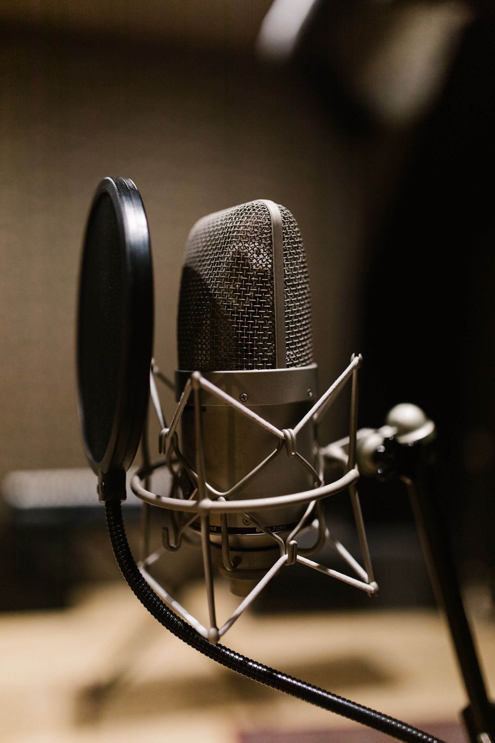 Microfone condensador com filtro pop sobre bancada em sala com isolamento acústico